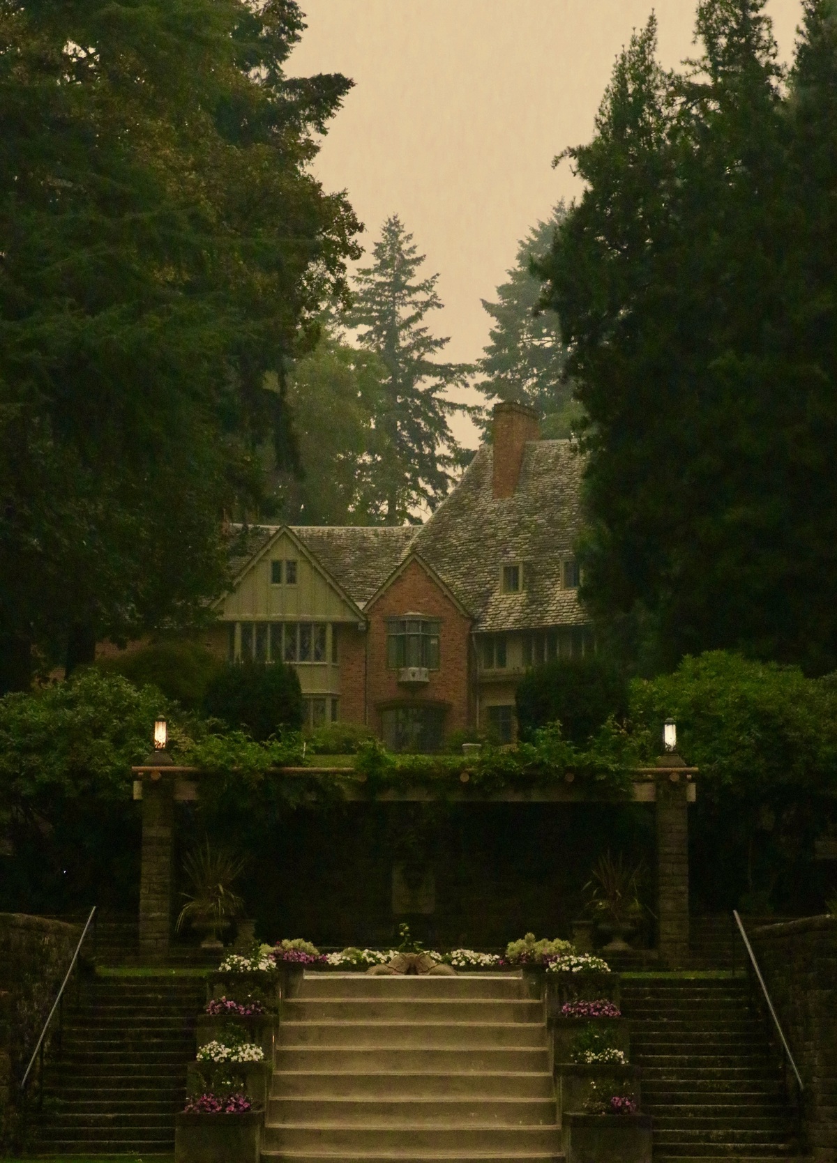 Photograph of Frank Manor House from the perspective of the Reflecting Pool in the foreground and a smoke-filled sky in the background.
