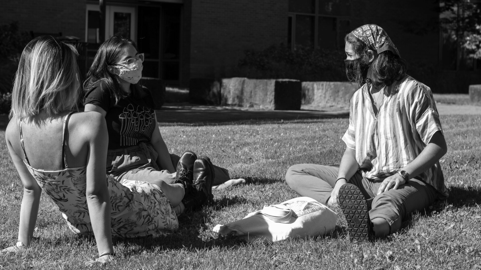 Students sit on the lawn wearing masks.