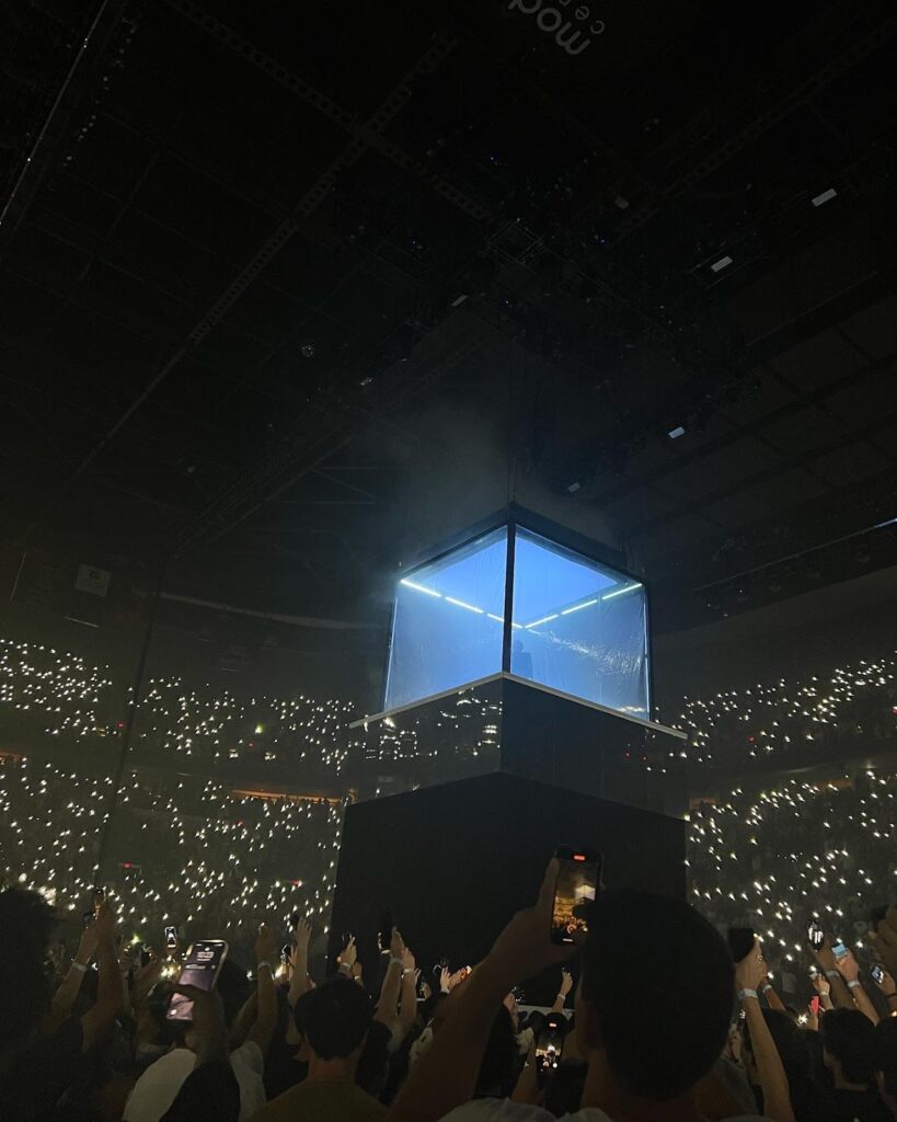 A cube is suspended over the audience.