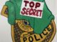 Illustration of a cloth with the words "TOP SECRET" partially covering a police badge.