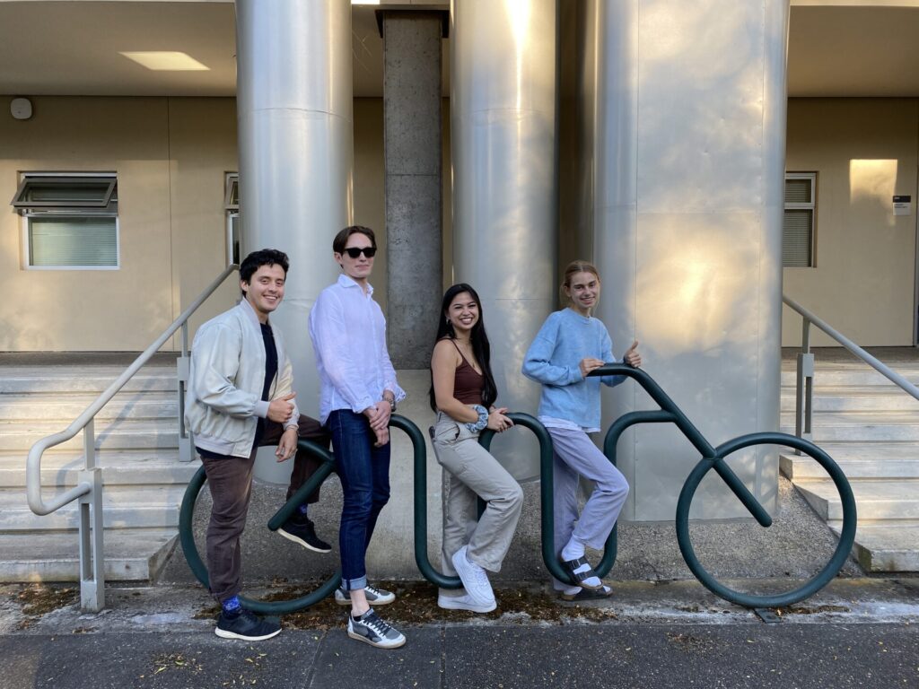 The four symposium co-chairs pose with a bicycle shaped bike rack.