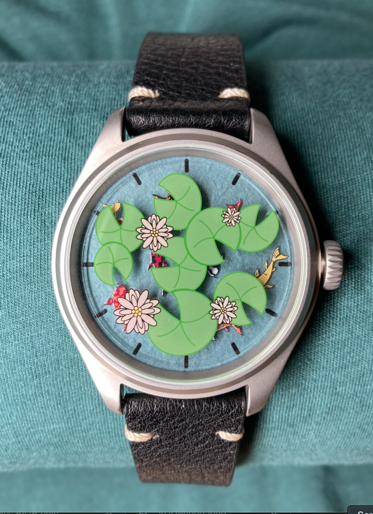 Photo of a watch with a blue face beneath lily pads, flowers, and hidden koi fish.