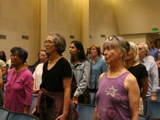 Choir members sing and stretch in auditorium