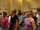 Choir members sing and stretch in auditorium