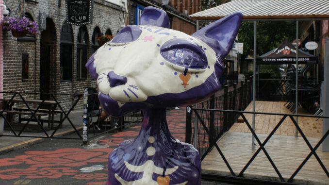 Photo of a cat sculpture; This "Cat" is purple and skeletal, one of the 30 scattered around Portland