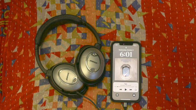 A photo of headphones connected to an iPhone playing "Tiger" by Christian Lee Hutson